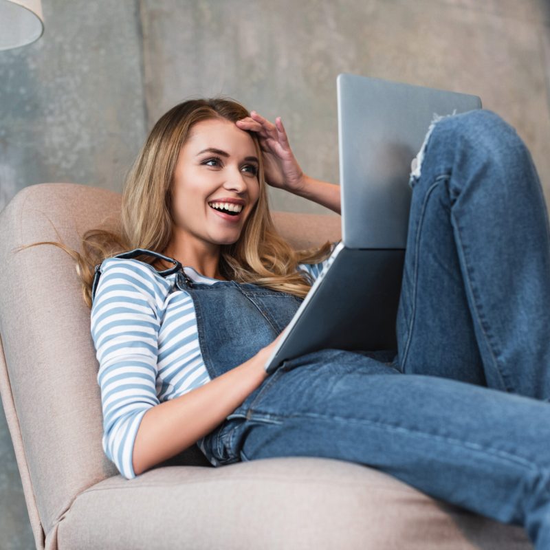 young girl smiling and surprised looking at monitor of laptop
